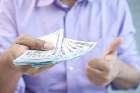 Close up of man holding us dollar and showing thumbs upの写真素材