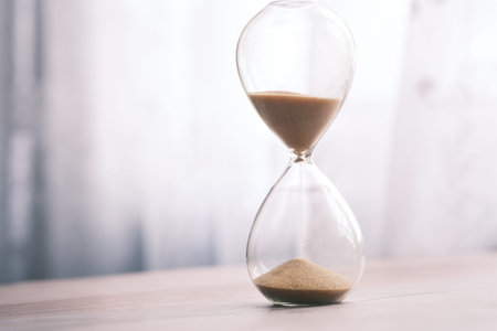 Hourglass on table, sand flowing through the bulb of sandglass