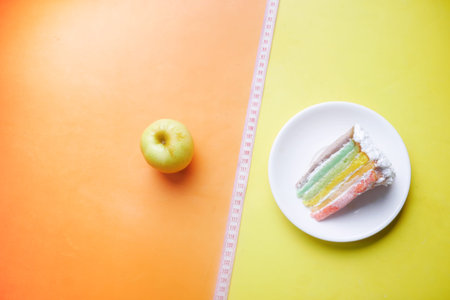 measuring tape, green apple and a bakery cake on color backgroundの写真素材