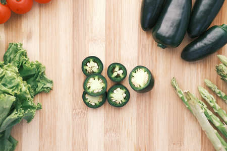 Jalapeno peppers , asparagus, cherry tomato, lettuce on chopping boardの写真素材