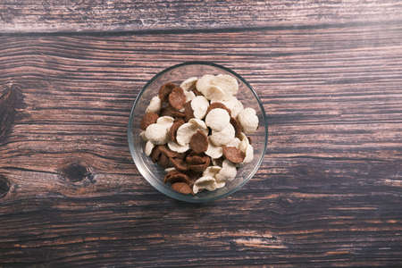 Top view of chocolate corn flakes in a bowl on wooden tableの写真素材