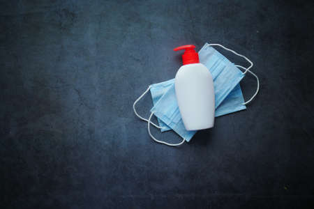 Surgical masks, and hand wash in a container on black background backgroundの写真素材