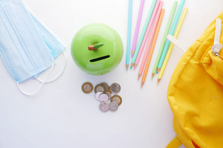 color pencils, face mask and coins on white background