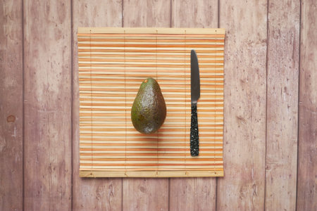top view of slice of avocado and knife on wooden table