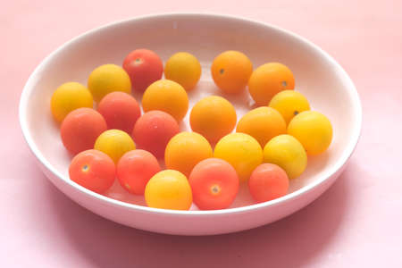 colorful cherry tomato on a plate on pinkの写真素材