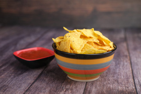 Bowl with tasty potato chips on wooden background .