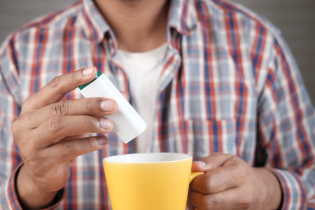young man putting artificial sweetener in tea,