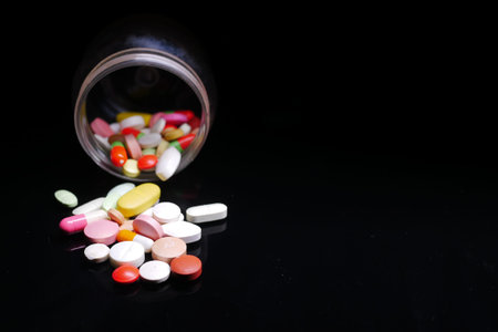 Close up of many colorful pills and capsules on black background