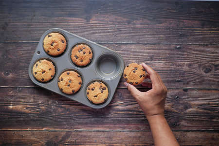 Top view of man hand holding chocolate cup cake on tableの写真素材