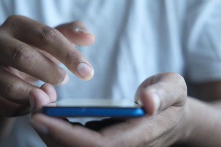 Close up of young man hand using smart phone.
