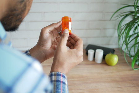 rear view of person hand holding pill containerの写真素材