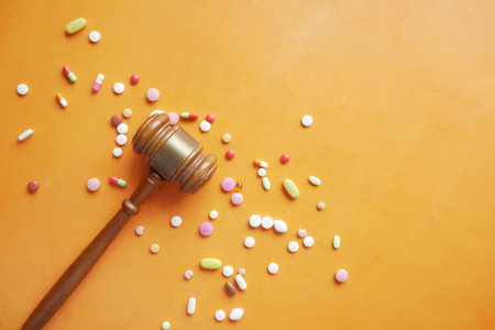 Top view of gavel, and medical pills on orange background