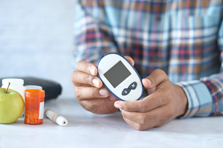 mans hand holding glucose meter while sited