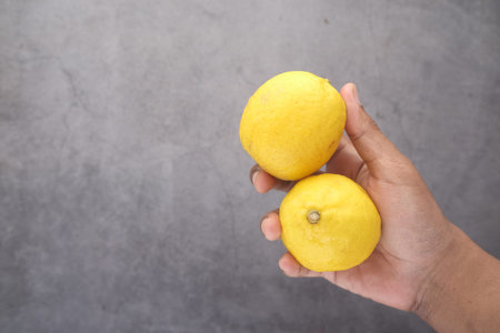 holding Yellow Lemon on black background