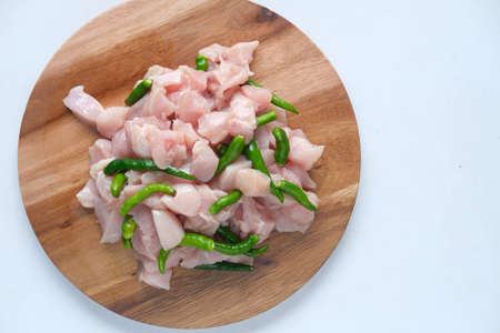 raw chicken slice and green chili on a chopping board on tableの写真素材