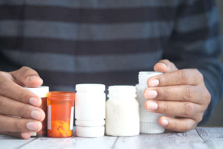 young man hand holding many medicine pill container white sitedの写真素材