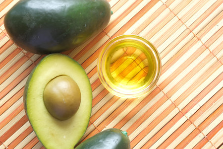 Top view of oil and slice of avocado on wooden table