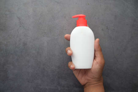 holding hand wash liquid in a container on black backgroundの写真素材