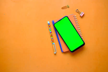 top view of smart phone and notepad on orange backgroundの写真素材