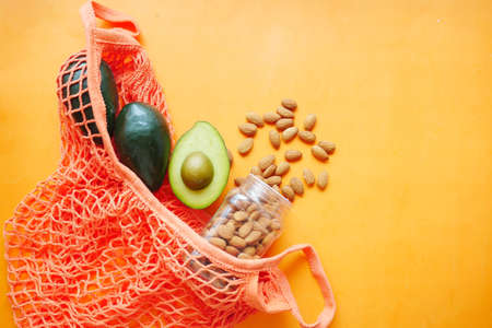 slice of avocado and almond nut in shopping bag on orange backgroundの写真素材