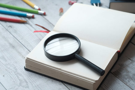 open book and magnifying glass on table.