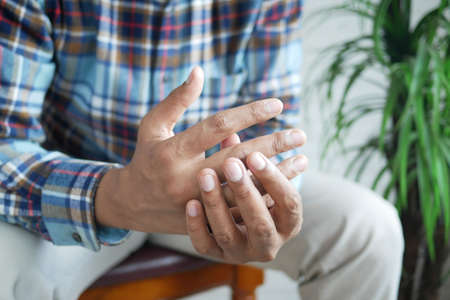 man suffering pain in finger while sitedの写真素材
