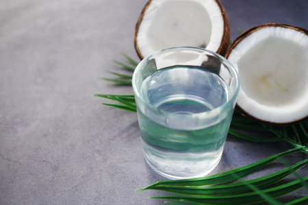slice of fresh coconut and glass of coconut water on tableの写真素材