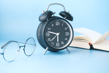 alarm clock , eyeglass and book on tableの写真素材