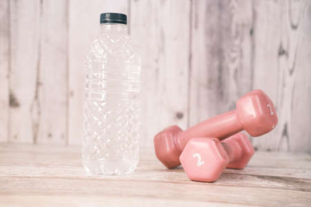 fresh drinking water and a pink color dumbbell on tableの写真素材