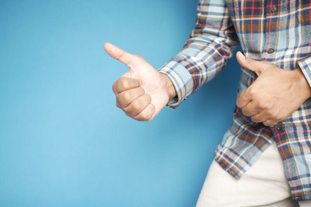 man hand showing a thumb-up on blue background