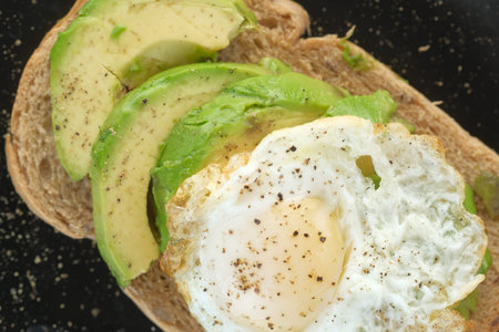 Avocado, brown bread, egg and rosemary on tableの写真素材