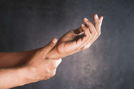 man suffering pain in hand against black backgroundの写真素材