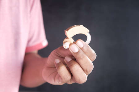 hand hold Hearing aid equipment isolated on blackの写真素材