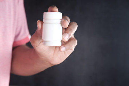 young man hand holding medicine pill container