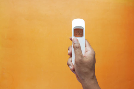 Hand holding infrared thermometer to measuring temperature.