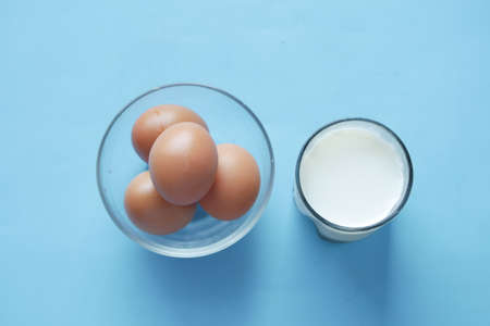eggs in a bowl and glass of milk on tableの写真素材