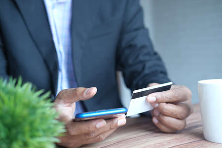 young man putting credit card detail on smart phoneの写真素材