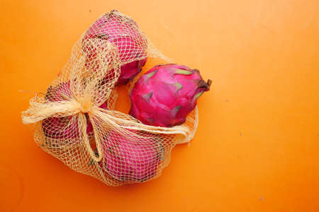 dragon fruit in a shopping bag on orange backgroundの写真素材