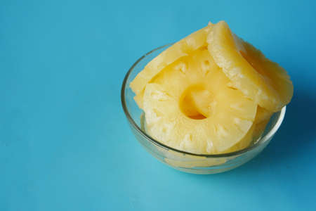 slice of pineapple in bowl on blue backgroundの写真素材