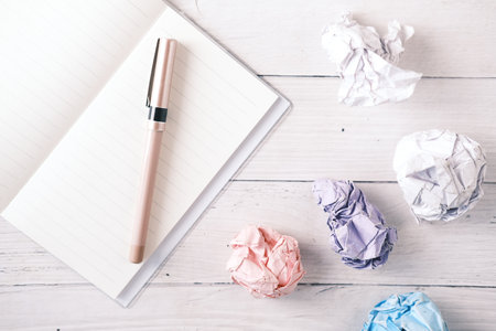 crumpled paper ball and notepad on wooden table.の写真素材