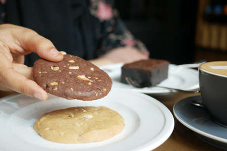 women hand pick cookies and tea on tableの写真素材
