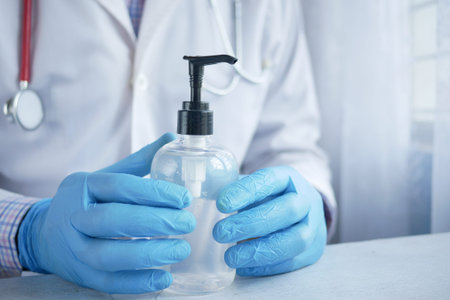 close up of doctor hand in latex gloves holding hand sanitizer