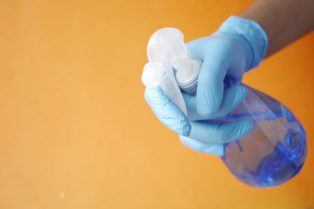 hand in blue rubber gloves holding spray bottleの写真素材
