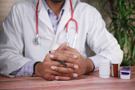 a nervous young doctors hand on table white sitedの写真素材