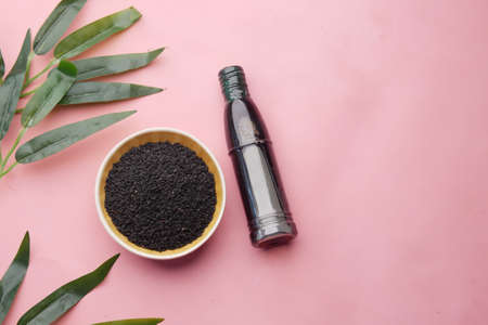 Black Cumin in a container with oil in a jar on pink.の写真素材