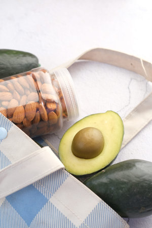 close up of slice of avocado and almond nut on chopping board.