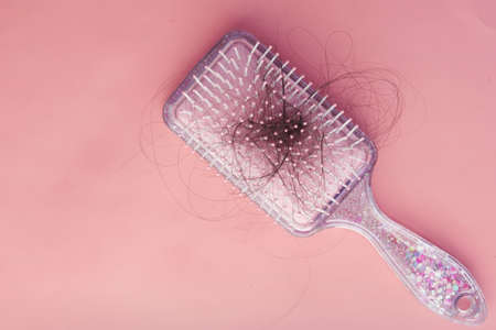 a brush with lost hair on pink backgroundの写真素材