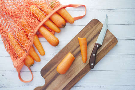 fresh carrots on chopping board on tableの写真素材