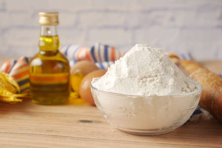 wheat flour in a bowl , egg and oil on tableの写真素材