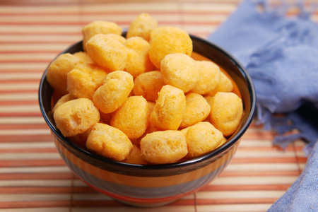 puffed corn rings chips in black bowl on white backgroundの写真素材